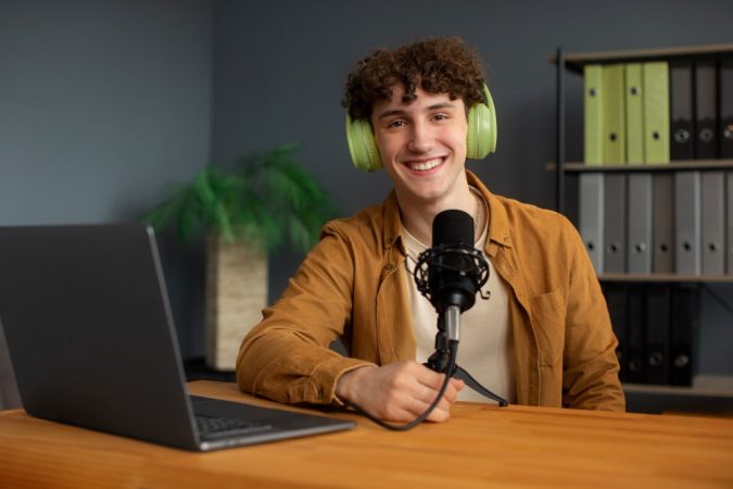 Jeune créateur de contenu souriant, équipement de podcast dans un studio Île-de-France professionnel.