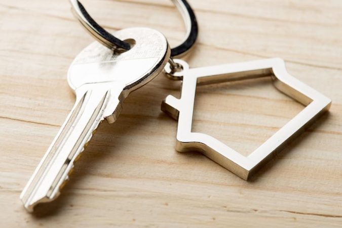 Une clé de maison et son porte-clé en métal sur un bureau en bois pour comprendre l'Assurance loyer impayé (GLI) sans CDI : quelles solutions pour les freelances et indépendants ?