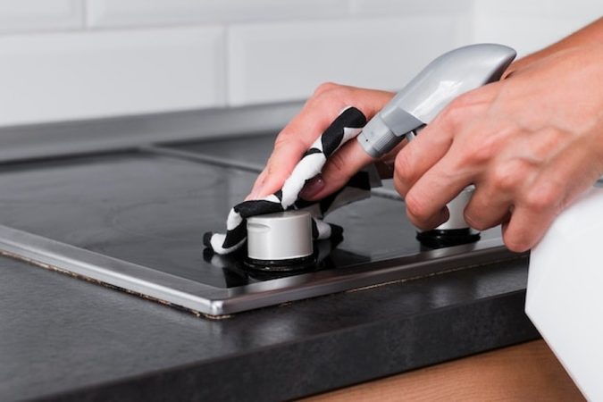 Entretien minutieux d'une surface de cuisson après avoir effectué un branchement plaque induction et four sur une seule prise : les solutions conformes à la norme NF C 15-100 garantissent une sécurité maximale.