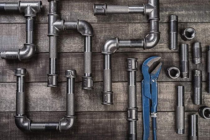 Tuyaux métalliques et clé à molette bleue prêts pour réparer un bruit de canalisation qui claque : comment identifier et stopper le coup de bélier définitivement.