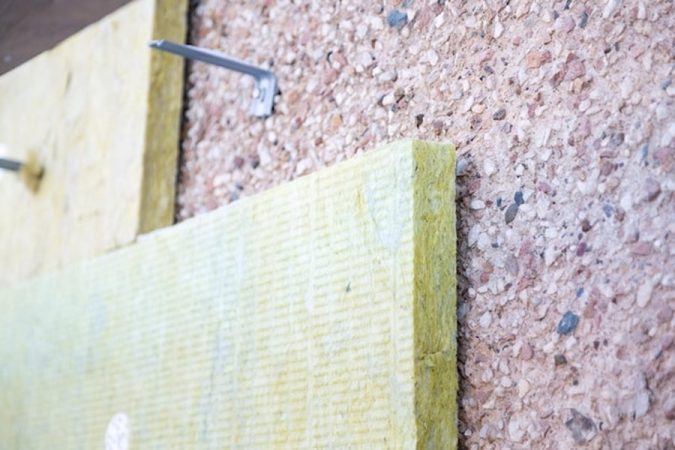 Pose de panneaux isolants sur une paroi ancienne pour découvrir comment isoler un mur en pierre par l'intérieur sans créer d'humidité : le guide technique complet.