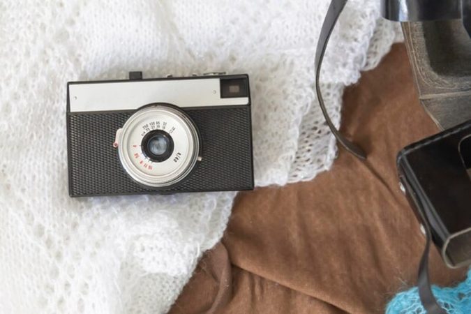 Un boîtier vintage compact posé sur une maille blanche, idéal pour illustrer comment obtenir l'esthétique 'Digicam' des années 2000 avec un smartphone ou un appareil photo moderne.