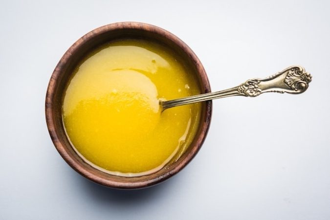 Ghee doré parfaitement réalisé dans un bol en bois rustique, illustrant le résultat final lorsque l'on maîtrise Comment Obtenir un Beurre Clarifié Sans Traces d'Humidité (Technique Pâtissière & Point de Fumée Élevé).