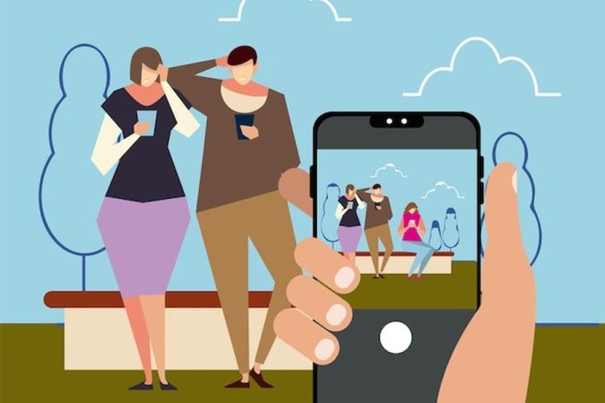 Une main tenant un smartphone cadre des personnes aux tenues soignées dans un parc pour montrer comment photographier ses vêtements pour Vinted : le guide ultime pour vendre plus vite.