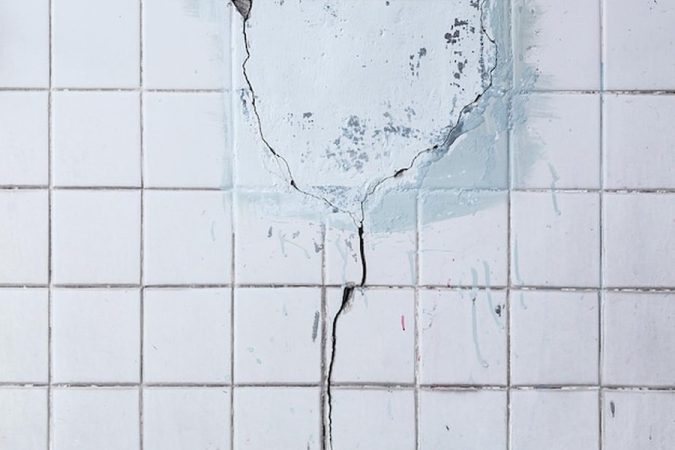 Une fissure verticale sur une surface sanitaire blanche montrant l'importance de savoir comment réparer un receveur de douche en résine fissuré sans le changer.