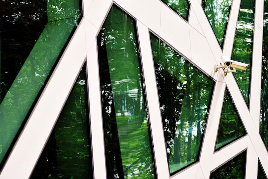 Une façade géométrique moderne aux panneaux de verre reflétant la forêt environnante, emblème de la green architecture.