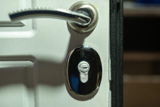 Un cylindre de serrure de porte blanche obstrué et inutilisable, illustrant le problème : Ma clé tourne dans le vide : diagnostic et solutions pour ouvrir votre porte sans tout casser.