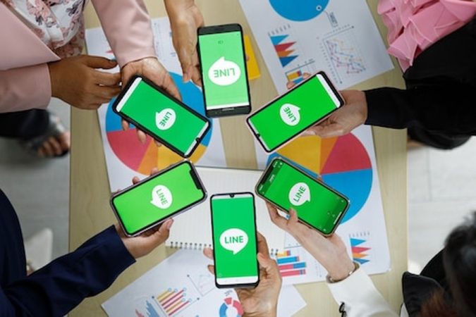 Plusieurs mains tiennent des smartphones affichant des applications de messagerie au-dessus de graphiques de performance, illustrant les principes de la Publicité sur WhatsApp Business : Le guide complet pour vendre sans passer par Facebook Ads.
