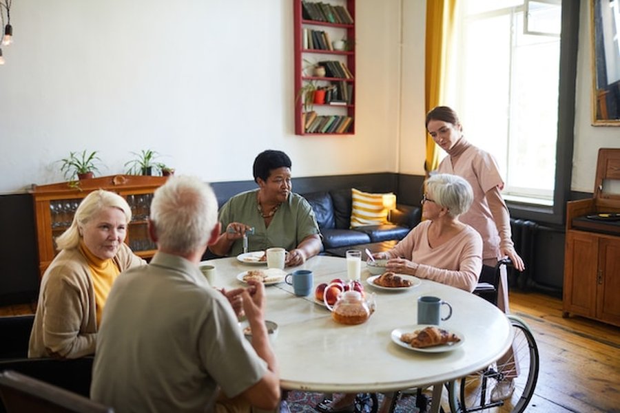 Un groupe de retraités partage un petit-déjeuner convivial au sein d'un espace de senior co-living baigné de lumière.