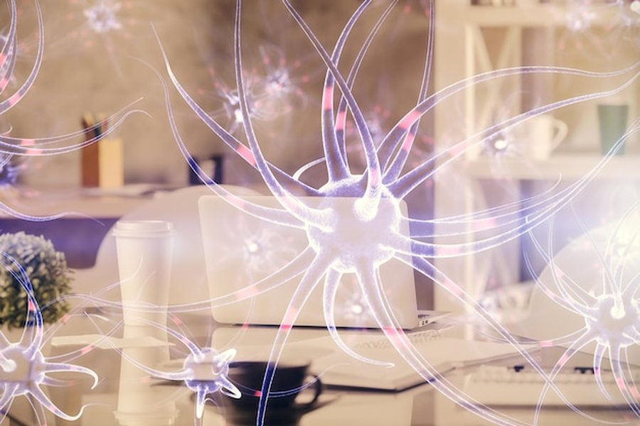 Des neurones lumineux flottent au-dessus d'un bureau épuré, illustrant concrètement comment aménager un sanctuaire de neuro-esthétique chez soi pour réguler son système nerveux.