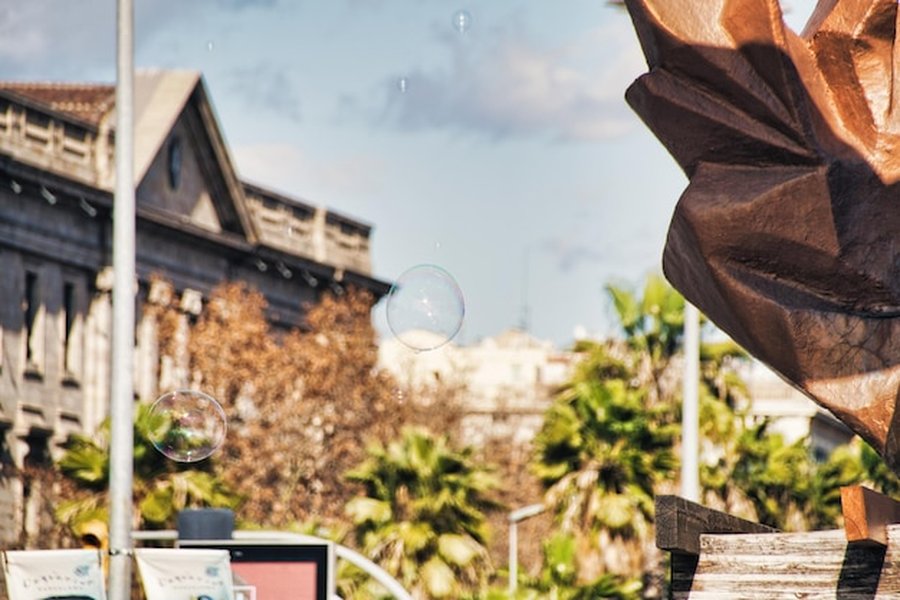 Des bulles de savon flottent devant des bâtiments historiques et des palmiers, une scène parfaite pour illustrer les Destination Swaps : les alternatives secrètes aux villes les plus touristiques d'Europe.