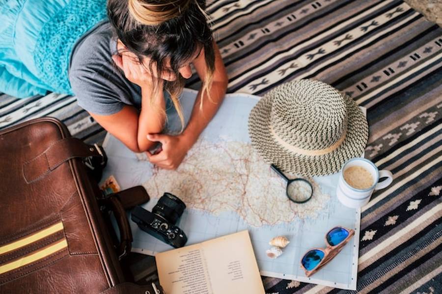 Une voyageuse étudie attentivement une carte pour planifier ses prochaines destinations de substitution : 12 alternatives incroyables pour éviter le surtourisme.
