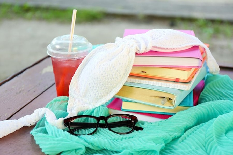 Une sélection de livres, une boisson glacée et des accessoires de détente pour suivre Le guide de la Coolcation : comment choisir sa destination fraîcheur pour échapper à la canicule.