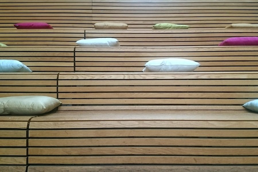 Gradins en bois clair et coussins confortables au sein d'une pièce de déconnexion sensorielle : créer un espace de bien-être acoustique et serein.