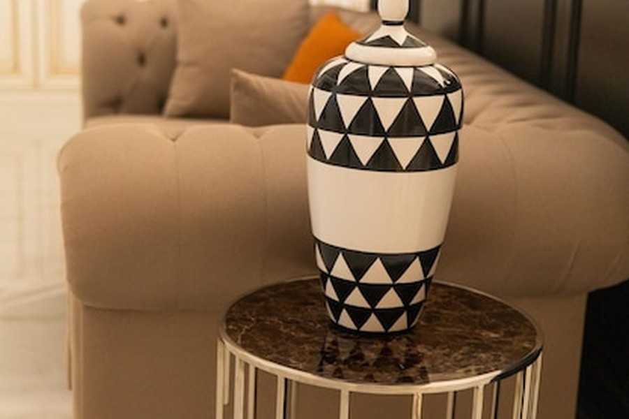 Un vase en céramique aux motifs graphiques noir et blanc sur une table en marbre, illustrant les tendances décoration salon 2026.