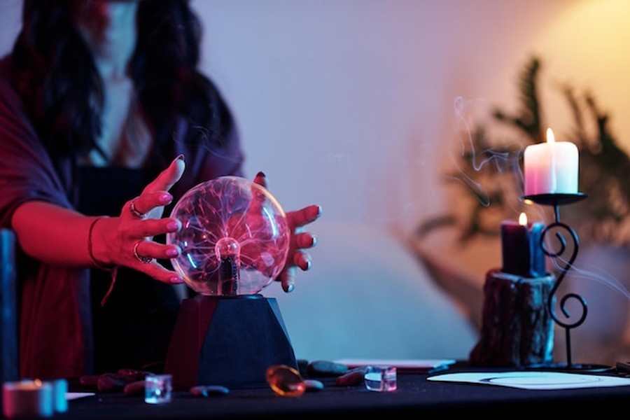 Une voyante manipulant une boule de cristal lumineuse dans une ambiance ésotérique, une mise en scène idéale pour apprendre comment démasquer une consultation de voyance générée par intelligence artificielle.