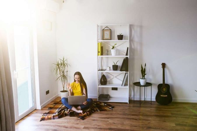 Une jeune femme assise sur le sol d'un salon lumineux avec une guitare acoustique, illustrant l'importance d'isoler acoustiquement une pièce pour profiter de la musique sans déranger.