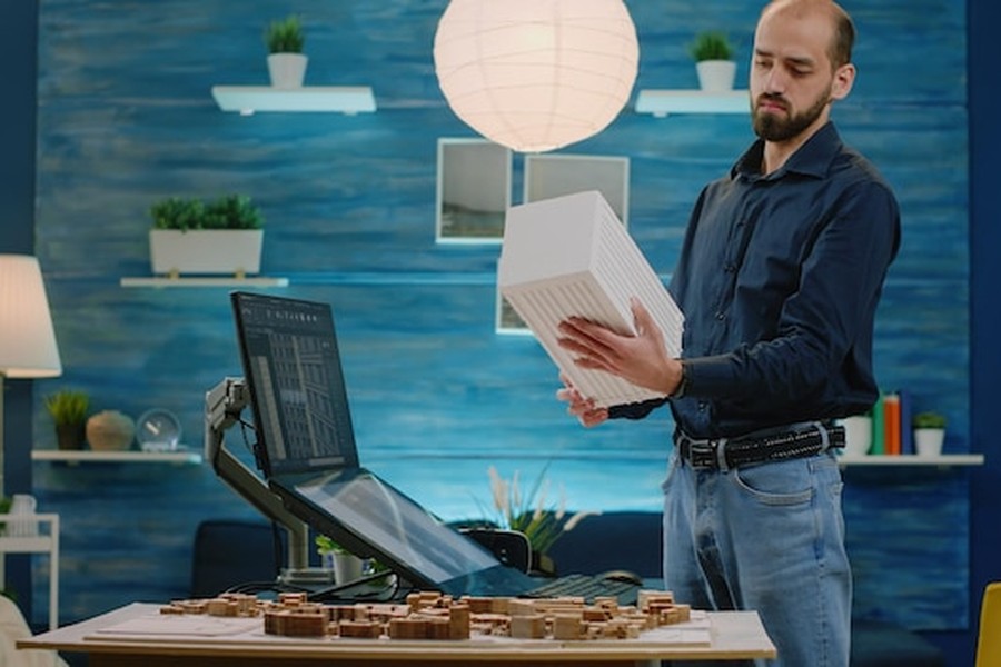 Un architecte inquiet examine ses projets en se demandant comment faire annuler un licenciement décidé par un algorithme suite à une erreur technique.