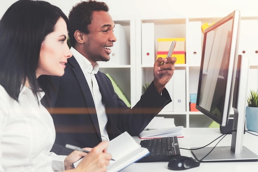 Deux experts en marketing digital collaborent devant un écran pour comprendre comment inscrire son entreprise dans les annuaires de confiance pour les moteurs de recherche génératifs.