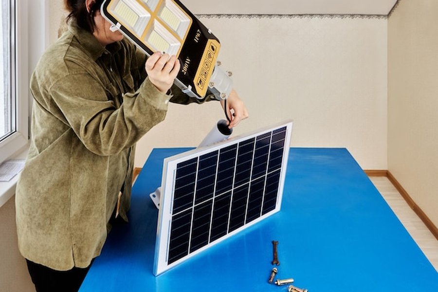 Une personne prépare l'assemblage d'un dispositif photovoltaïque sur un plan de travail bleu pour illustrer comment installer et entretenir une batterie domestique au sodium-ion pour l'autoconsommation solaire.