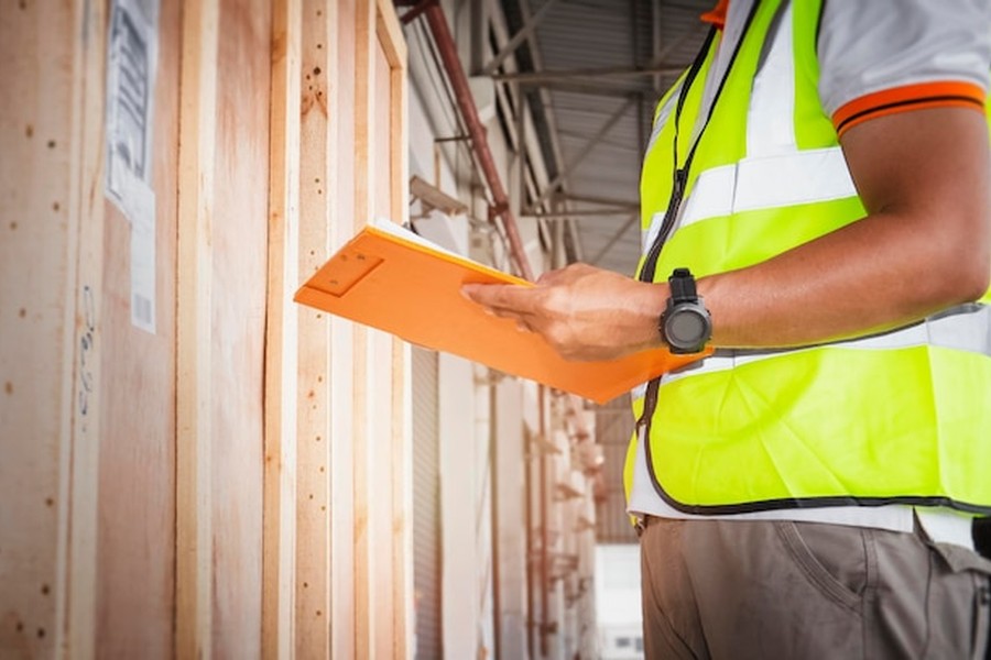 Un professionnel examine des structures en bois pour valider le réemploi de charpente bois : guide des certifications et garanties décennales.