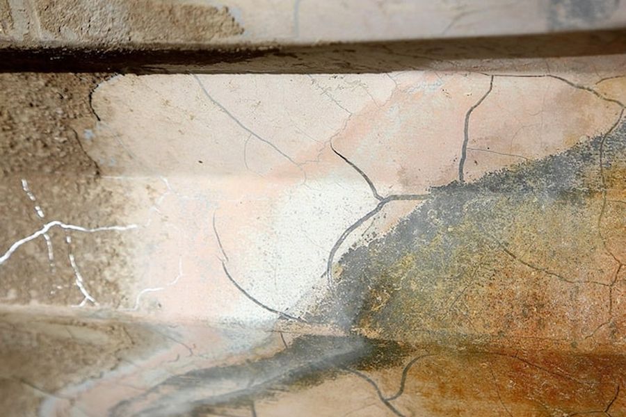 Des craquelures ramifiées apparaissent sur un enduit mural extérieur, illustrant comment réparer une fissure de sécheresse sur un mur sans attendre l'expert.