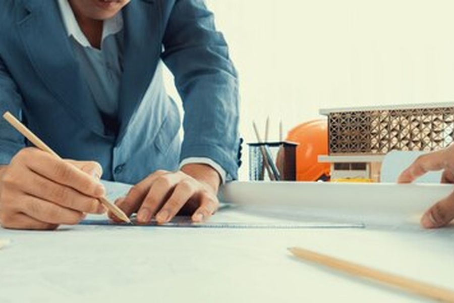 Un architecte travaillant avec précision sur des plans de construction, illustrant comment intégrer une signature d'authenticité infalsifiable à vos clichés professionnels.