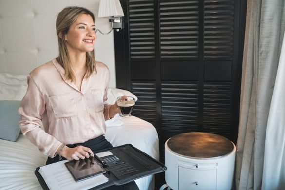 Une femme souriante examine ses plans pour savoir comment installer un générateur d'eau atmosphérique pour l'autonomie totale de la maison tout en savourant un café.