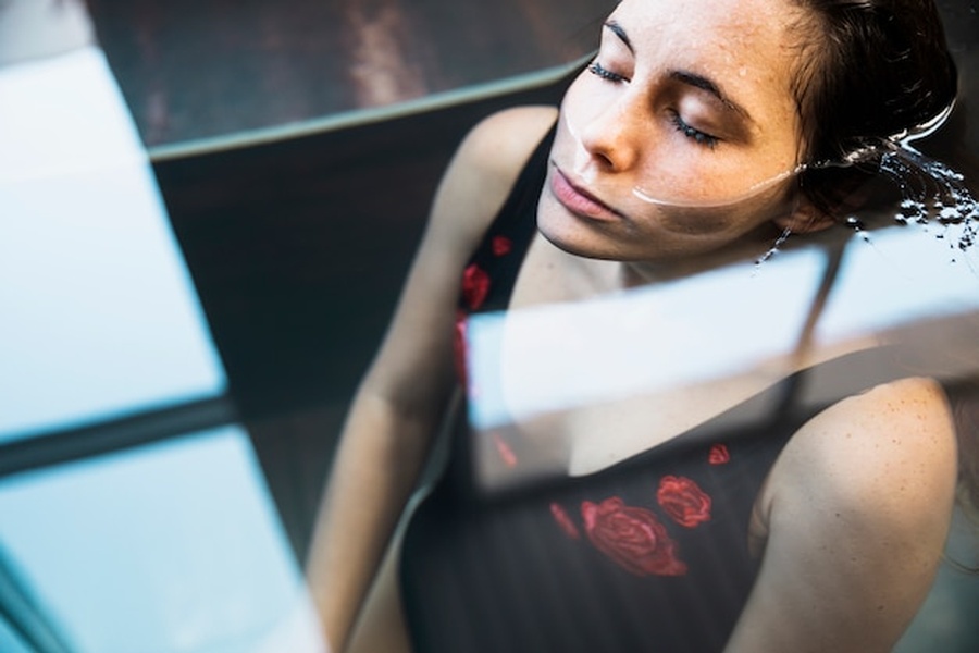 Une femme se repose dans l'eau claire pour apaiser sa peau après l'effort, illustrant pourquoi vous devriez vaporiser de l'acide hypochloreux sur votre visage après le sport.