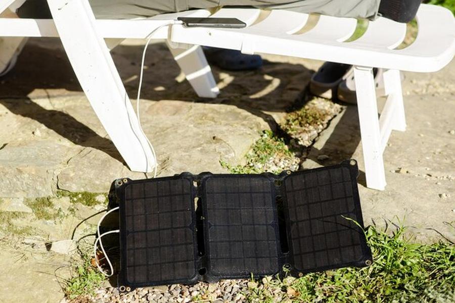 Un petit panneau solaire portable rechargeant un smartphone à l'extérieur, illustrant les principes de la Batterie domestique au sodium : le guide complet pour stocker son énergie solaire sans lithium.