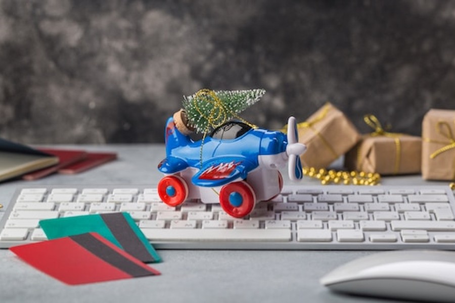 Un petit avion bleu transportant un sapin de Noël sur un clavier d'ordinateur pour illustrer comment bloquer la collecte de données sur les nouveaux jouets IA de votre enfant.
