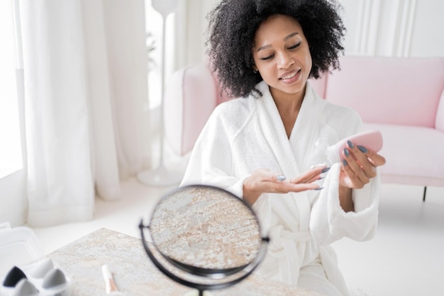 Une femme à la peau éclatante applique un soin hydratant, illustrant comment synchroniser sa routine beauté sur son cycle hormonal pour une peau parfaite.