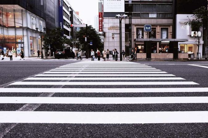 Un passage piéton urbain à Tokyo entouré de gratte-ciels, symbolisant la solitude numérique et comment réagir quand votre enfant préfère discuter avec son IA plutôt qu'avec ses amis.