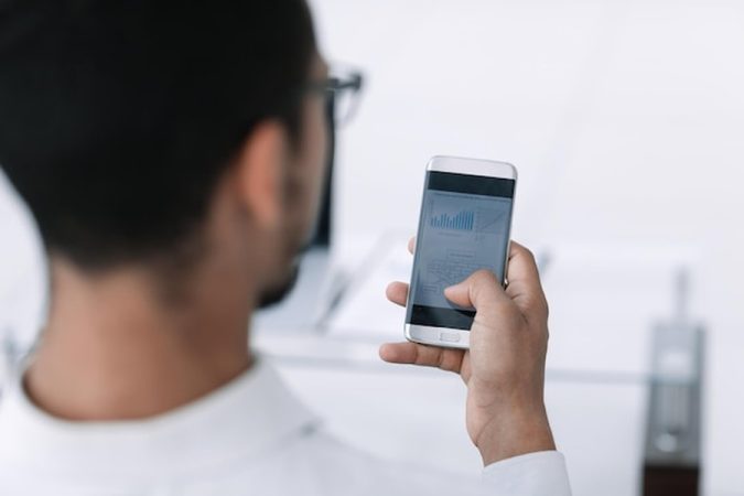 Un professionnel analyse des graphiques de données sur son smartphone protégé par un antivirus pour android gratuit.