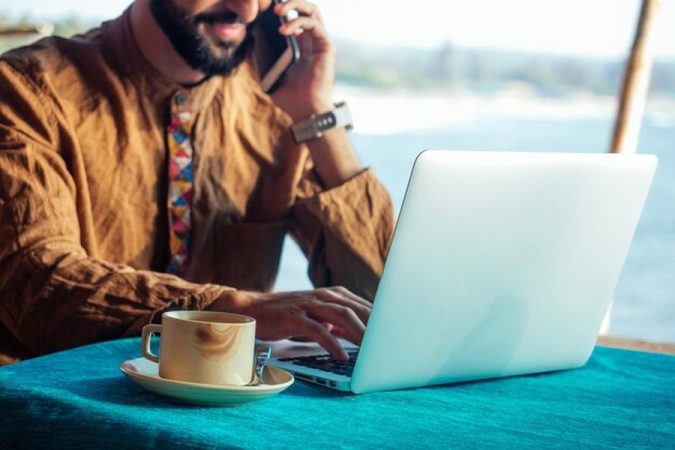 Une femme professionnelle travaille sur son ordinateur portable depuis une terrasse ensoleillée à Marrakech avec une vue imprenable sur la ville.