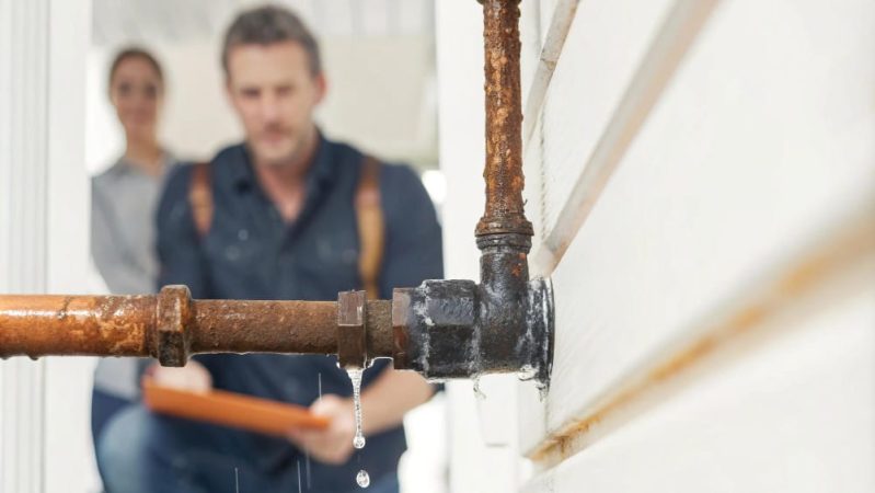 Gouttes d'eau s'échappant d'un raccord de tuyauterie métallique rouillé nécessitant une recherche de fuite d'eau