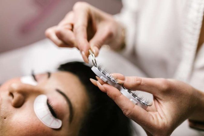 Un technicien prépare des extensions pour des cils fragiles avec une pince.
